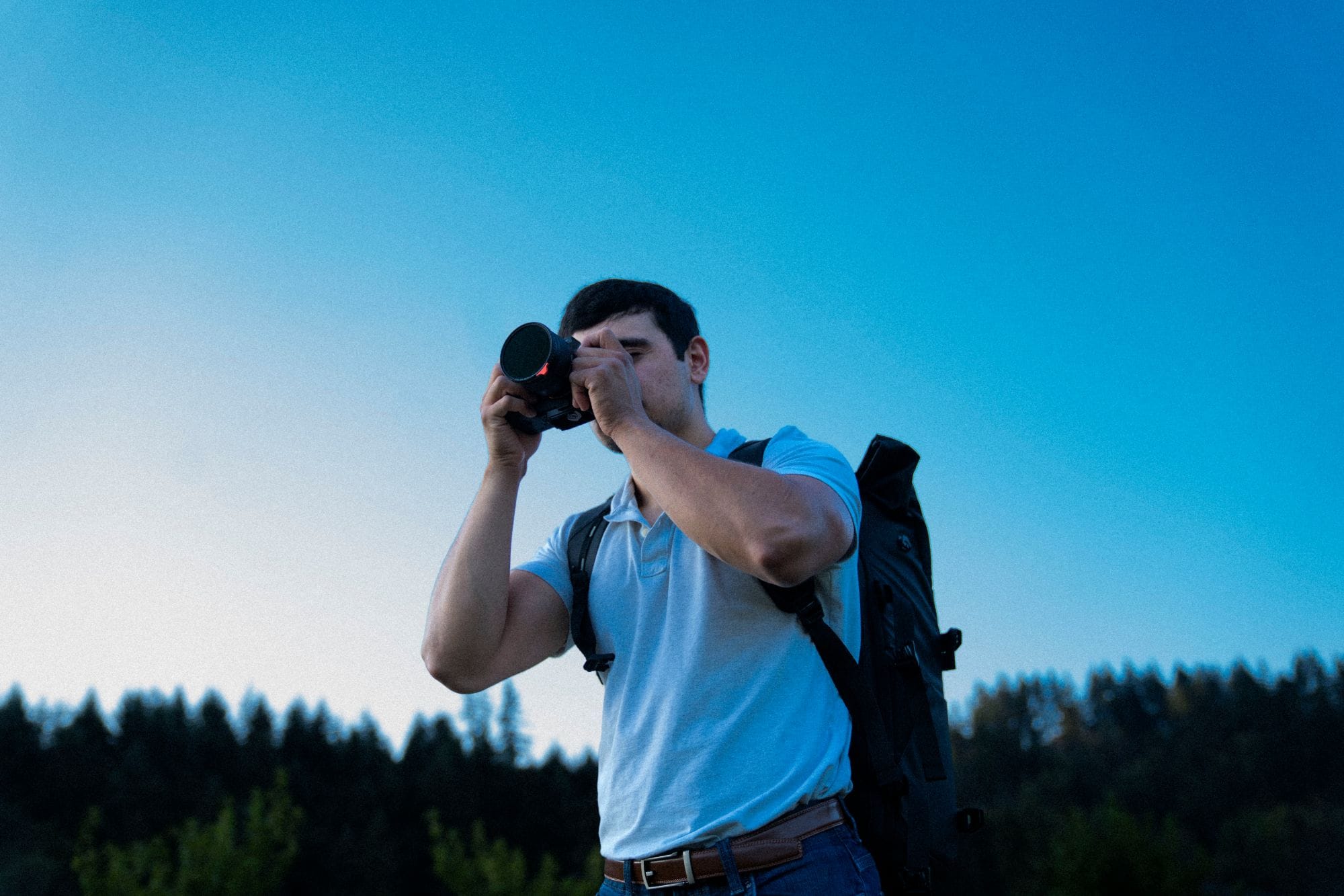 DJ Riley framing a shot with his camera against a blue evening sky
