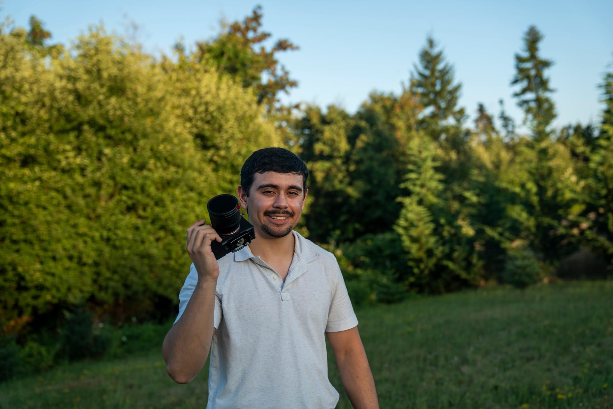 DJ Riley smiling and holding his camera at golden hour
